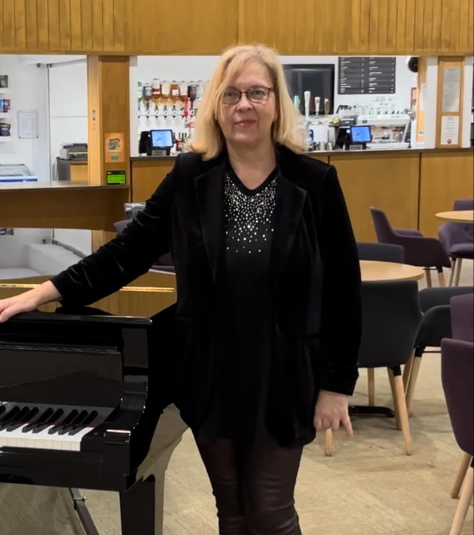 Caroline standing by piano.