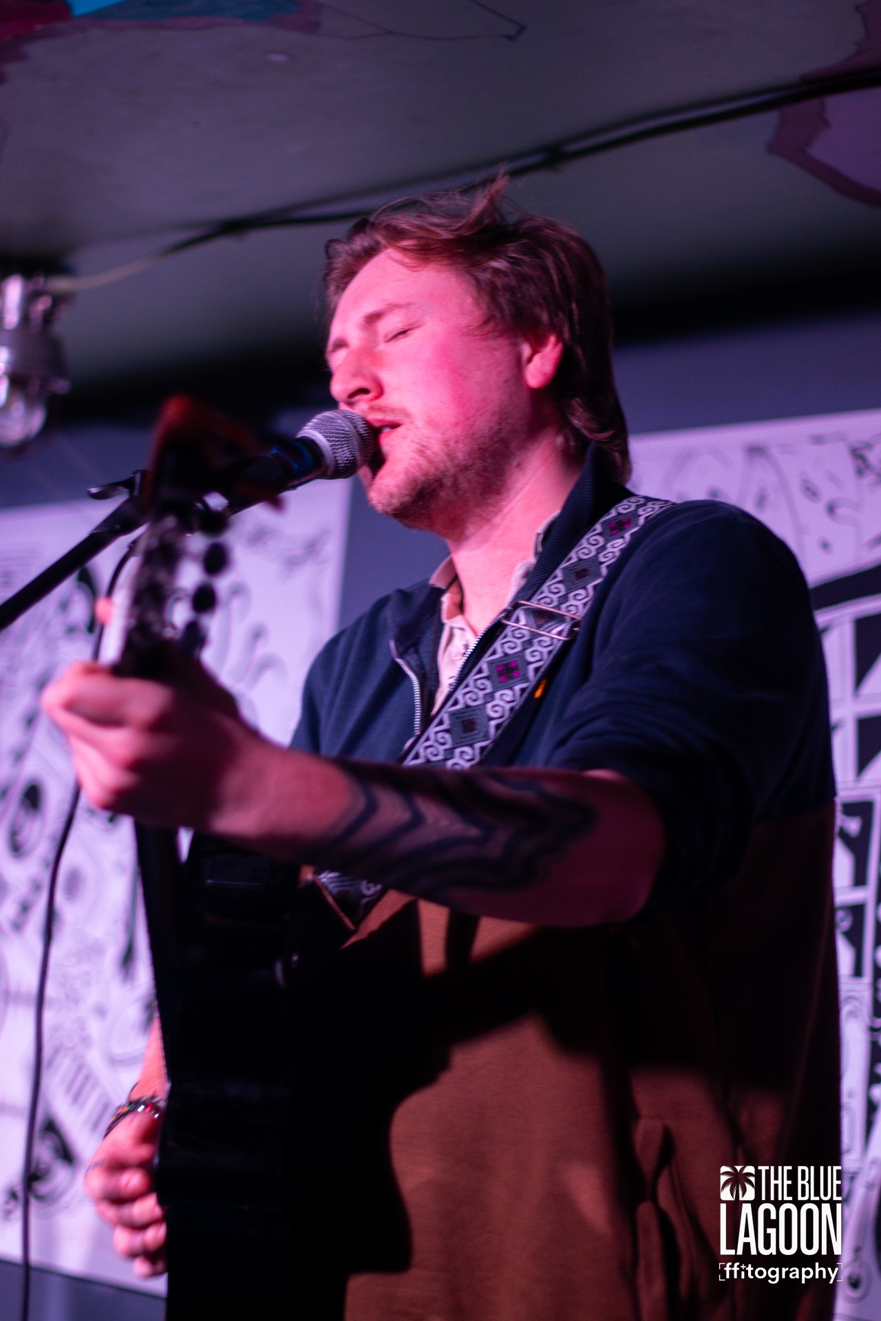 Daniel playing a guitar and singing into a microphone